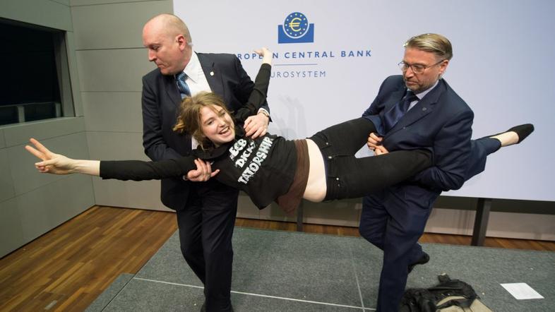 Ženska protestira na tiskovni konferenci ECB.