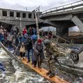 Prečkanje uničenega mostu pri begu iz mesta Irpin v regiji Kijev.