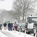 Vozniki stojijo ob avtih po tem, ko so obtičali v snegu, ki je pobelil severno A