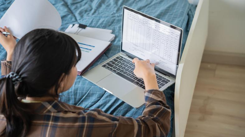 Mlada punca študentka z računalnikom na postelji