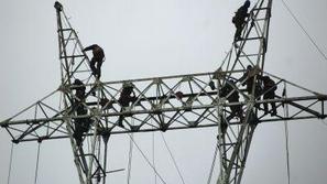 Kitajski delavci odpravljajo škodo snežnega neurja na električnih daljnovodih.