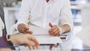 Pisarniški delavci sedijo in pregledujejo papirje