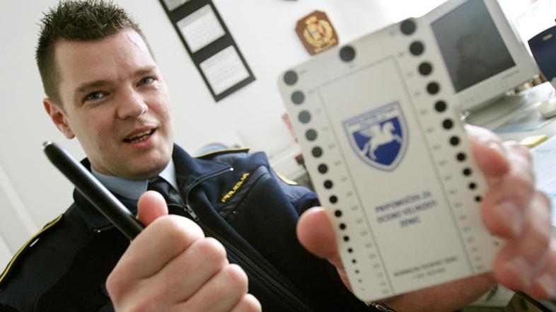 Peter Leban v roki drži šablono z velikostmi zenic in baterijsko svetilko. To je