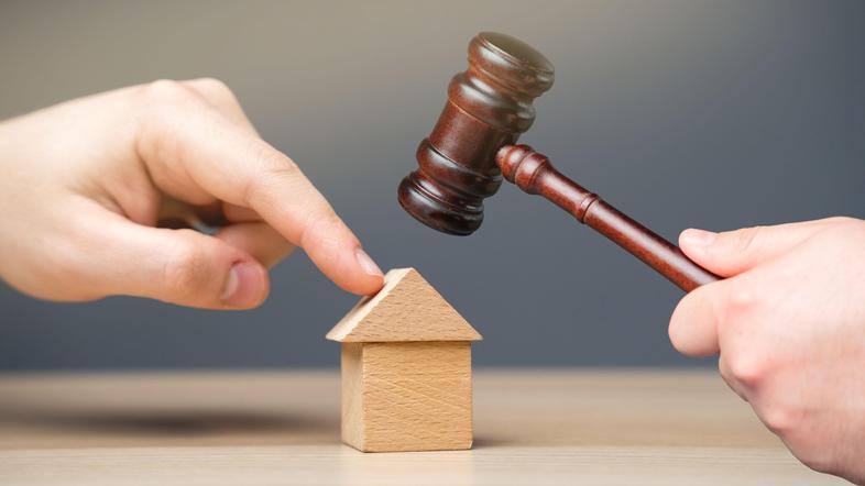 zapuščina prst na leseni hiški in sodniško kladivo