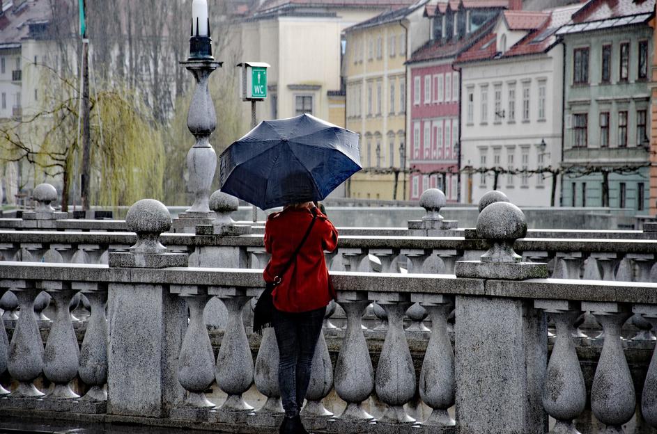 Ljubljana dež ženska z dežnikom stoji na mostu