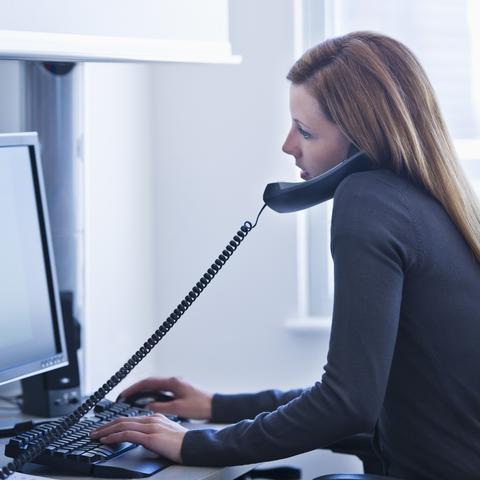 Ženska telefonira ob računalniku