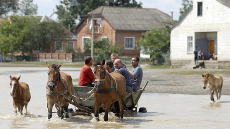 Namesto z avtomobili se Ukrajinci po poplavljenih cestah vozijo s kočijami.
