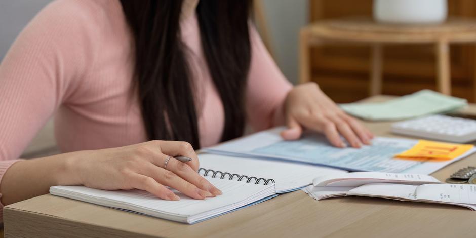 Ženska za mizo s papirji in kalkulatorjem | Avtor: Profimedia