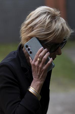 Starejša ženska z očali in telefonom v roki