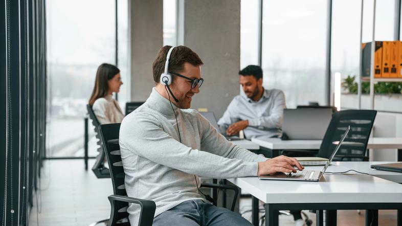 Moški v pisarni s slušalkami