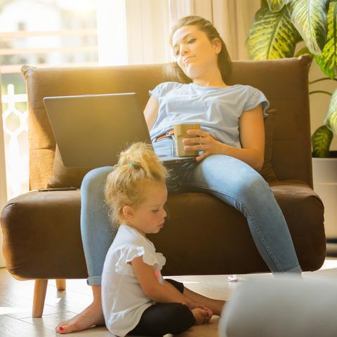 Utrujena ženska z otrokom dela na računalniku