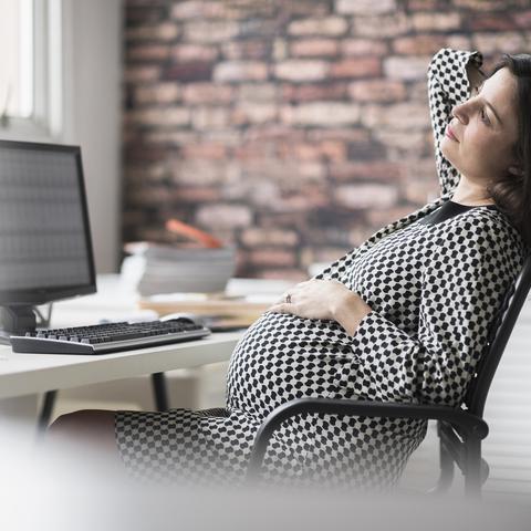 nosečnica sedi na stolu v pisarni