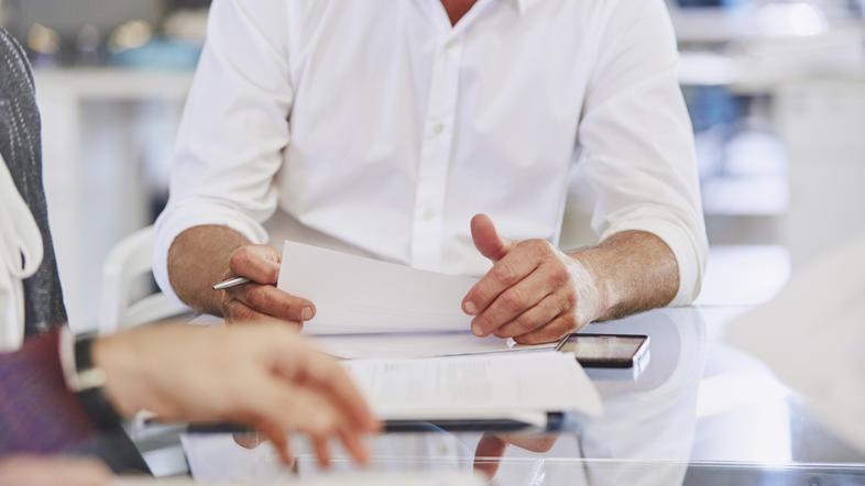 Pisarniški delavci sedijo in pregledujejo papirje