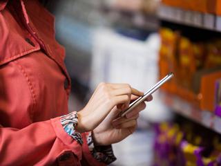 Ženska v roki drži telefon v trgovini
