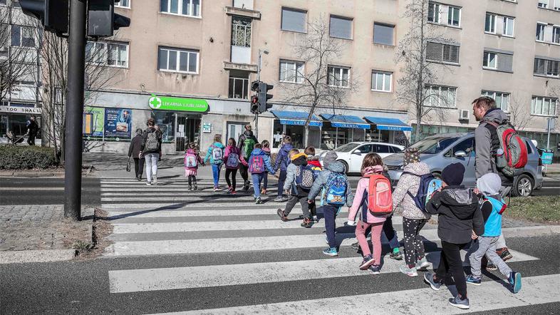 šolski otroci v spremstvu prečkajo cesto