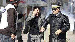 Policist med današnjimi protesti za roko vodi protestnika, ki je onemogočen zara