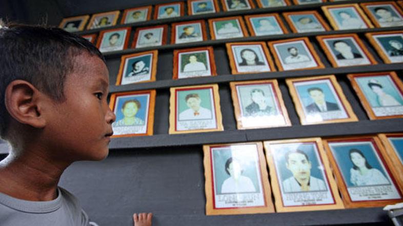 Otrok iz Kambodže stoji pred spominsko steno le dela žrtev virusa HIV.