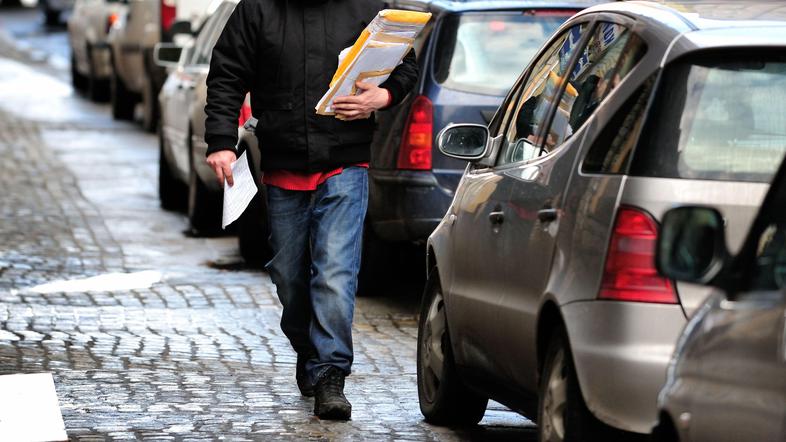 Moški s paketom hodi po ulici