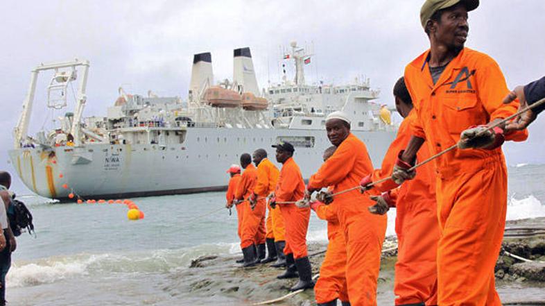 Delavci v pristaniškem mestu Mombasa na plažo vlečejo del optičnega kabla, ki je