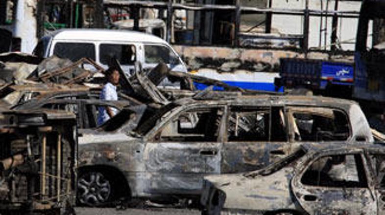 Moški med avtomobili, ki so jih uničili med neredi pretekli teden.