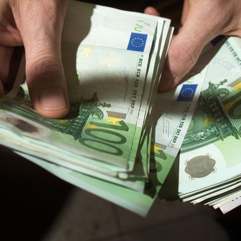 Moški v roki drži denar evre