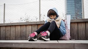 žalostna deklica brska po telefonu