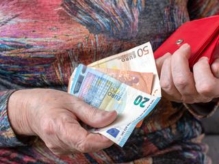 Upokojenka drži v rokah evre in denarnico