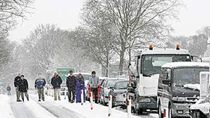Vozniki stojijo ob avtih po tem, ko so obtičali v snegu, ki je pobelil severno A