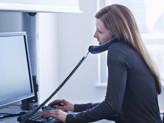 Ženska telefonira ob računalniku