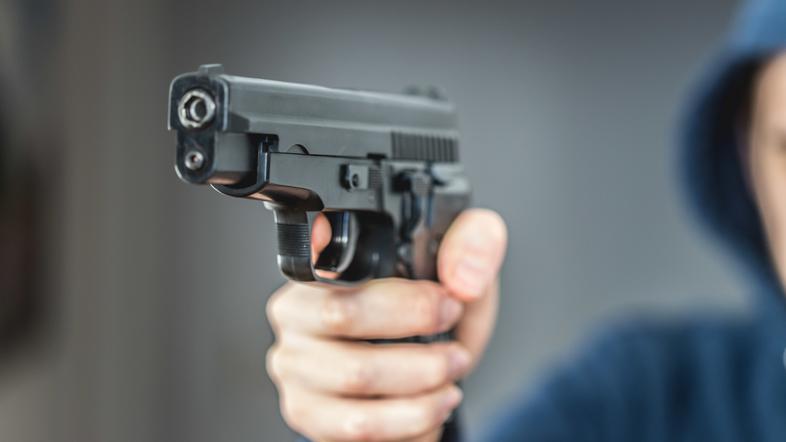 Rop s pištolo v roki - fotografija je simbolična