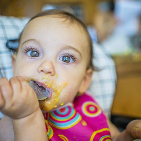 deklica sedi v stolčku in je pasirano hrano