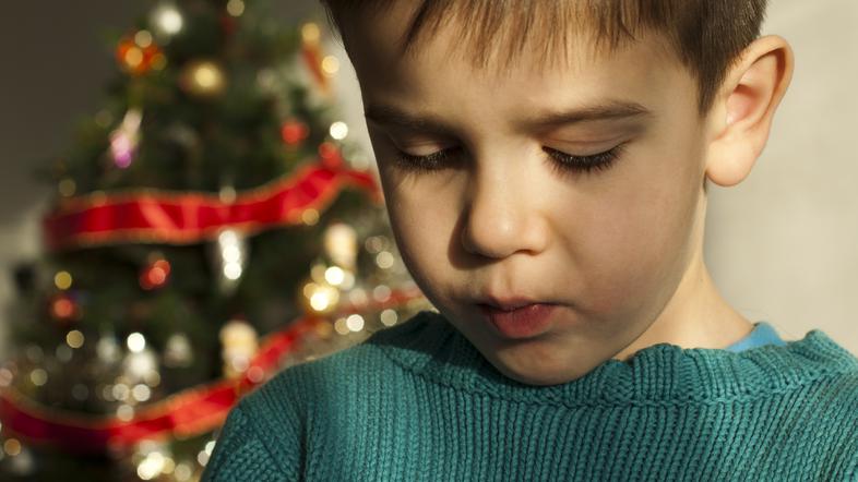 Žalosten fantek ob božičnem drevescu