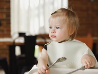 deklica sedi v stolčku za hranjenje