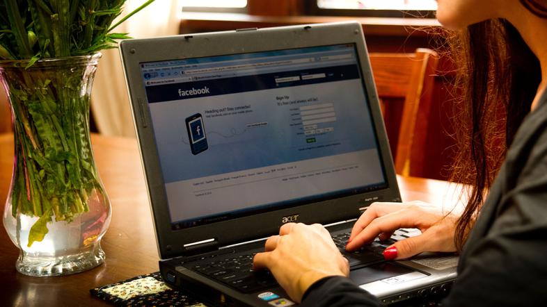 Ženska ob računalniku ima odprt Facebook