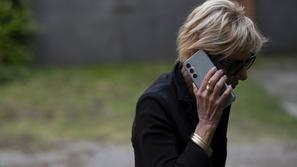 Starejša ženska z očali in telefonom v roki