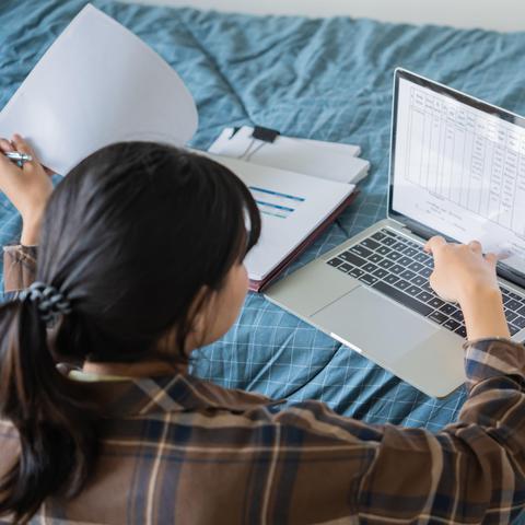 Mlada punca študentka z računalnikom na postelji