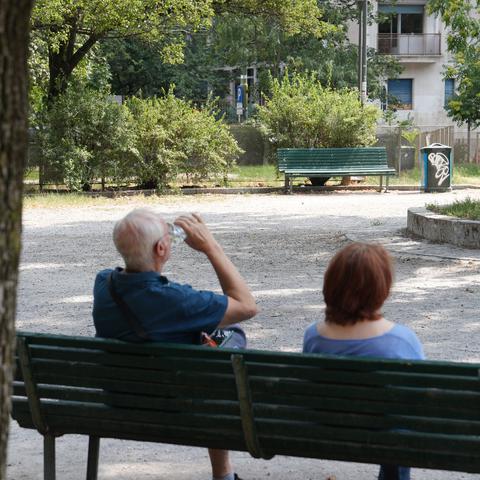 starejši moški in ženska sedita na klopi v senci vročinski val
