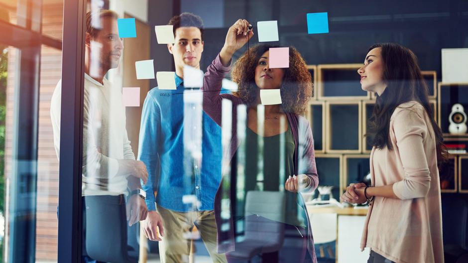 Mladi v pisarni delajo in lepijo listke na steklo | Avtor: Profimedia