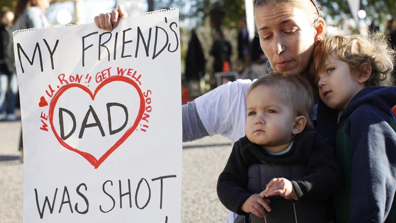 Susan Shobe z otrokoma kleči pred bolnišnico, kjer so se številni ljudje umrlim 