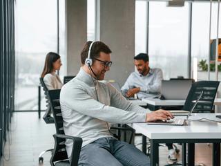 Moški v pisarni s slušalkami
