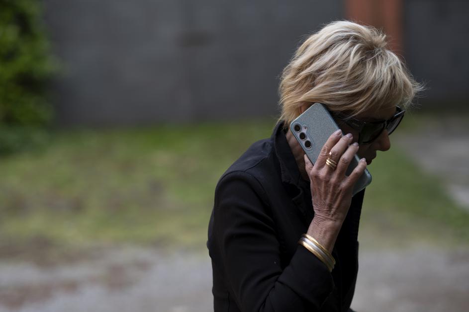 Starejša ženska z očali in telefonom v roki