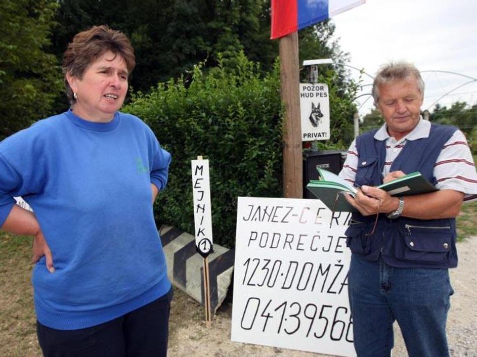 Marija in Janez Cerar stojita pred dovozom na svojo parcelo, okoli katere še ved