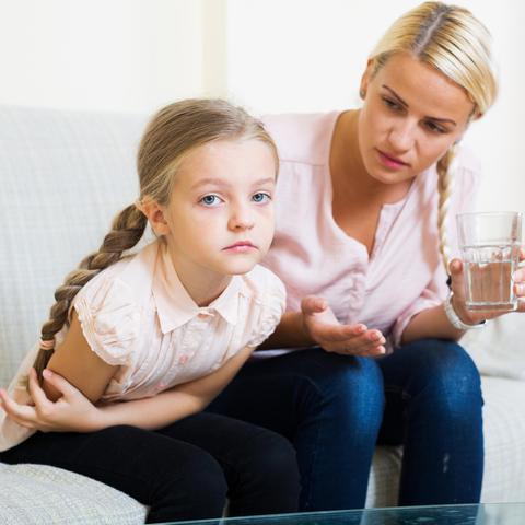 Mama otroku z bolečinami v trebuhu ponuja kozarec vode