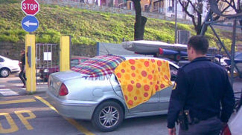 Policisti si ogledujejo prizorišče; avto Italijana je prekrit z odejami, ki naj 