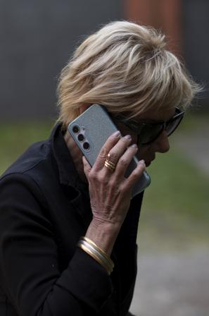 Starejša ženska z očali in telefonom v roki