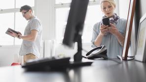 Ženska s telefonom in moški v pisarni