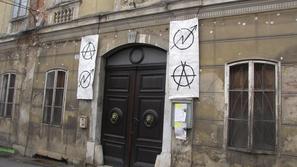 Simbola ob vratih pomenita anarhijo – družbo brez hierarhije – in skvot – okupir