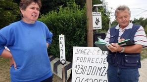 Marija in Janez Cerar stojita pred dovozom na svojo parcelo, okoli katere še ved