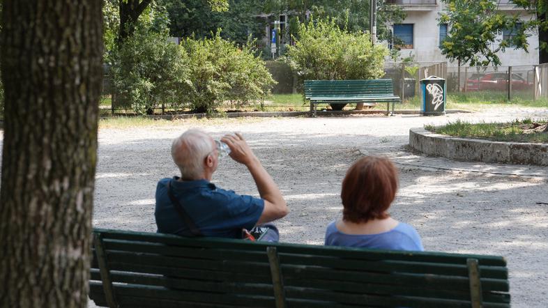 starejši moški in ženska sedita na klopi v senci vročinski val