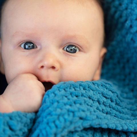 dojenček zavit v modro odejo